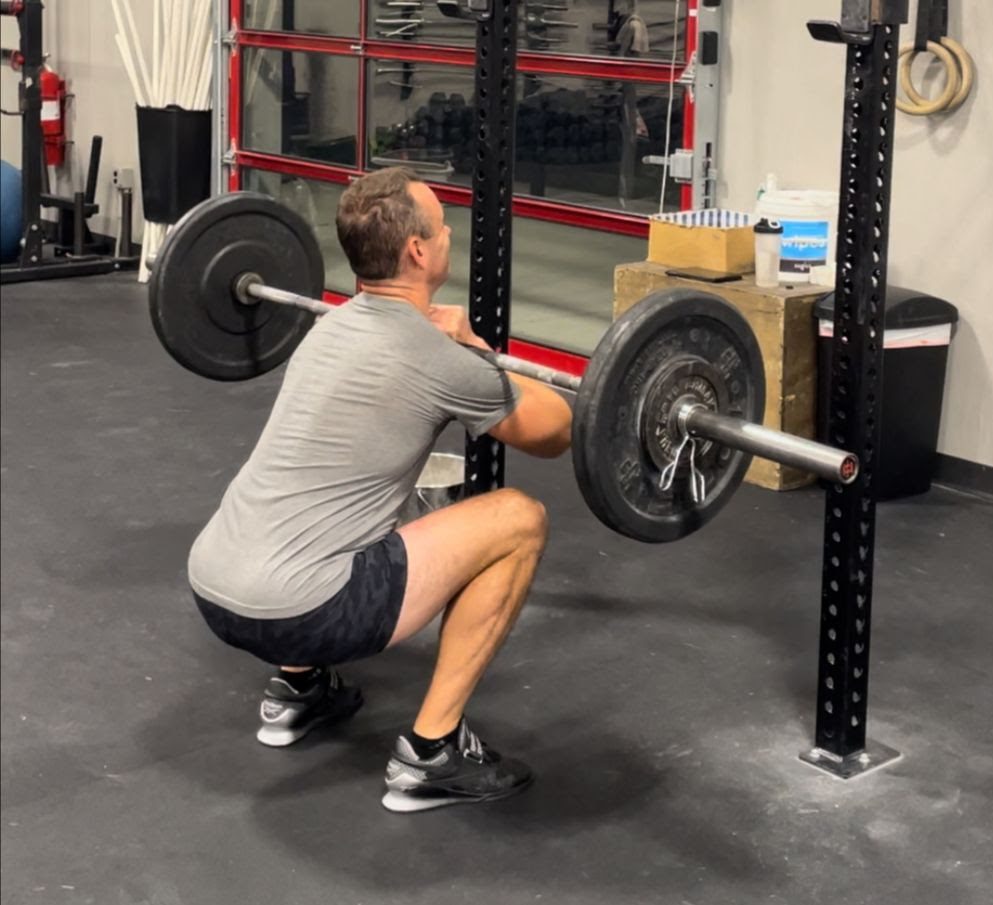 a man squatting a barbell as part of his physical therapy exercises