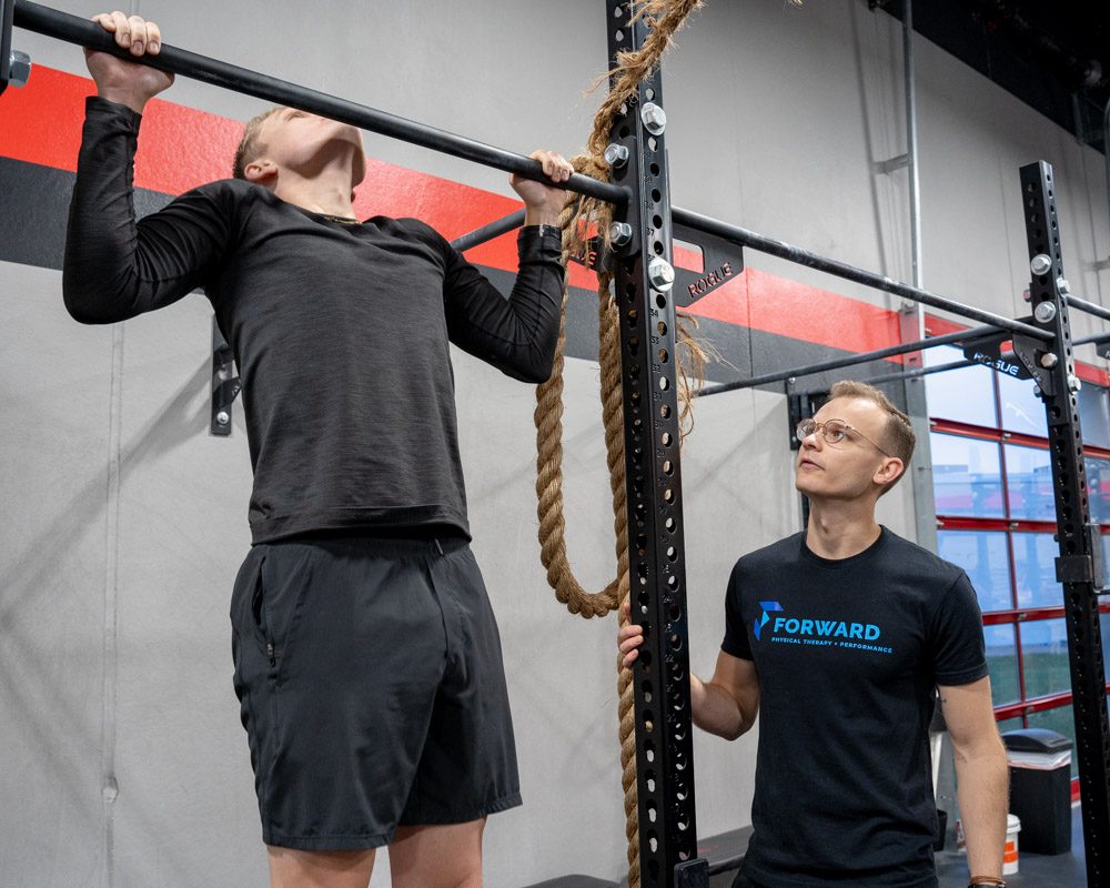 a man doing pull-ups as part of physical therapy in omaha